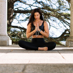 Woman in Black Tank Top and Black Pants Sitting on Concrete Floor