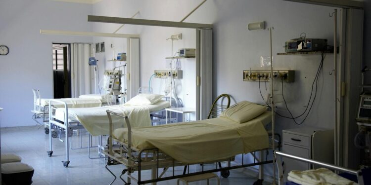 Spacious hospital room with several empty beds and medical equipment, emphasizing healthcare and hygiene.