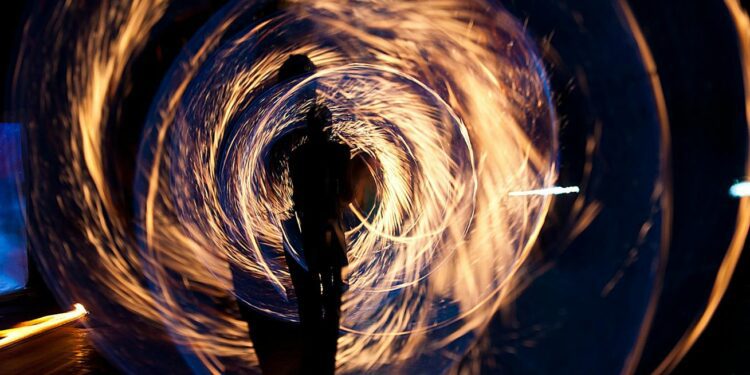 Mesmerizing long exposure shot of fire spinning and silhouette at night.