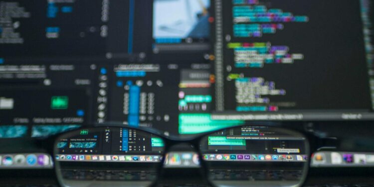 Eyeglasses reflecting computer code on a monitor, ideal for technology and programming themes.