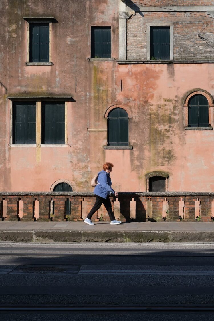 A woman walking by a rustic wall in historic Padova, capturing the charm of Veneto, Italy.