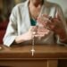 Close-up of a woman praying with a rosary in a church environment, symbolizing faith and spirituality.
