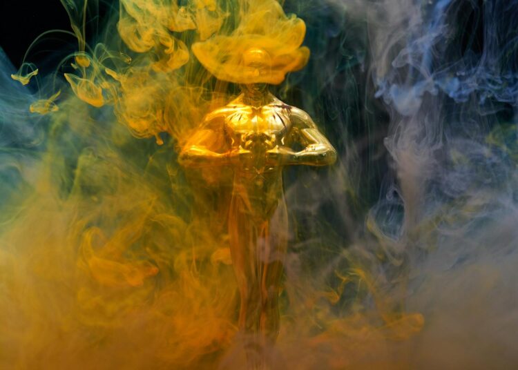 A golden statuette enveloped in vibrant yellow and blue smoke, symbolizing achievement and success.