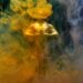 A golden statuette enveloped in vibrant yellow and blue smoke, symbolizing achievement and success.