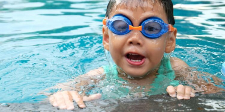 Young child playing and swimming in a pool, enjoying the water.