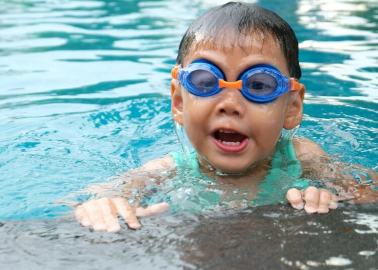 Young child playing and swimming in a pool, enjoying the water.