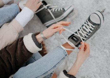 Women tying shoelaces on ice skates on a snowy winter day. Perfect for lifestyle and winter sports themes.