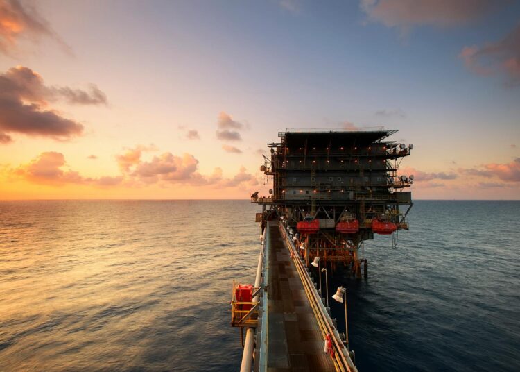 A breathtaking view of an oil platform on the ocean at sunset, showcasing industrial beauty.
