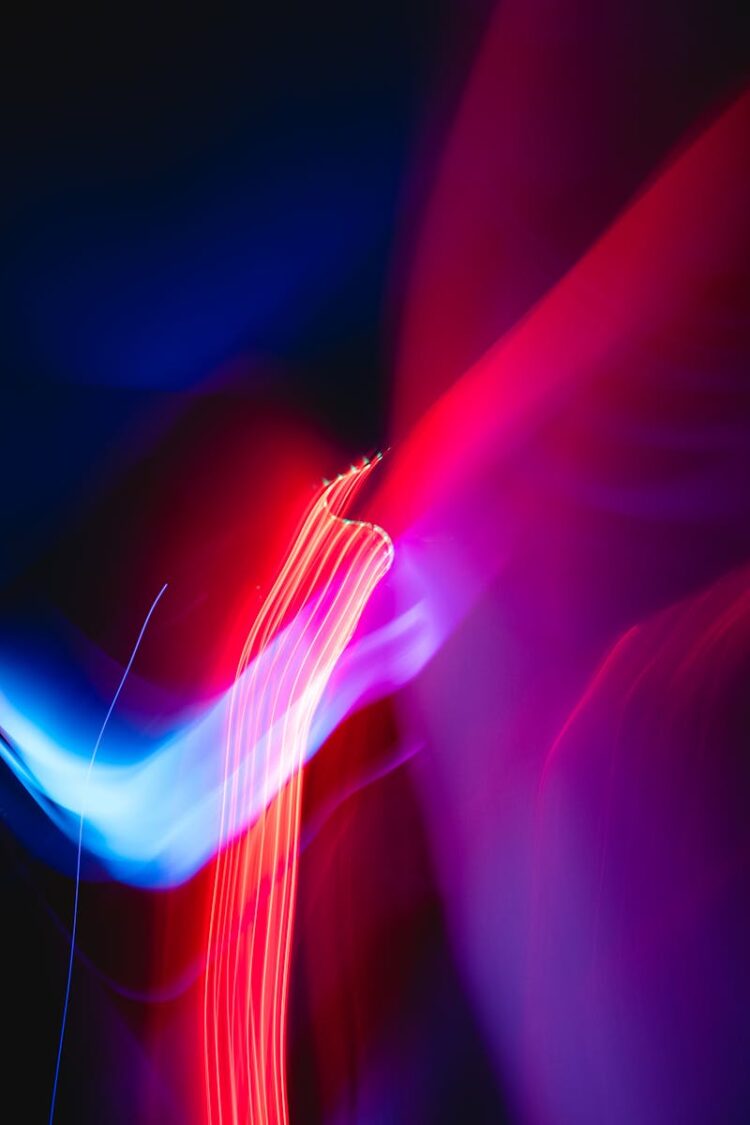 Vibrant abstract image with dynamic red and blue light streaks over a dark background.
