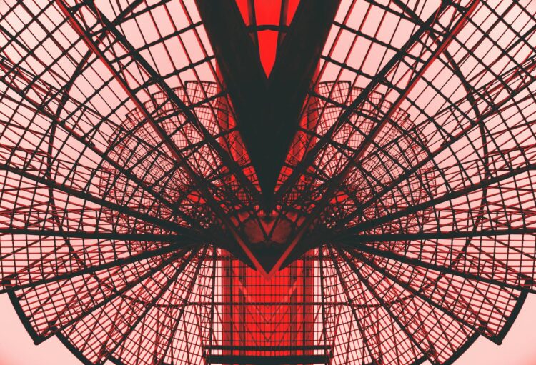 Abstract view of a red geometric architectural structure, showcasing modern design and symmetry.