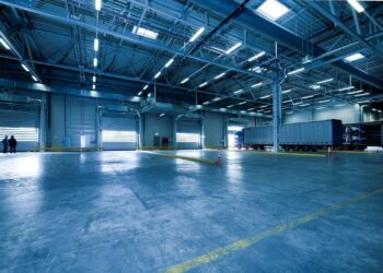 Wide view of an empty modern warehouse with industrial lighting and trucks.