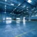 Wide view of an empty modern warehouse with industrial lighting and trucks.