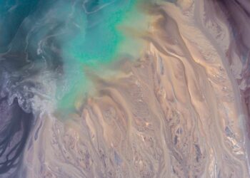 Stunning abstract aerial view showcasing turquoise waters blending with sandy textures, ideal for creative backgrounds.