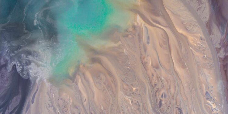 Stunning abstract aerial view showcasing turquoise waters blending with sandy textures, ideal for creative backgrounds.