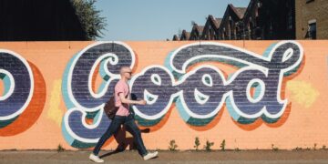 man walking beside graffiti wall