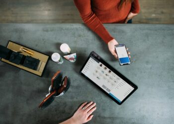person holding smartphone beside tablet computer