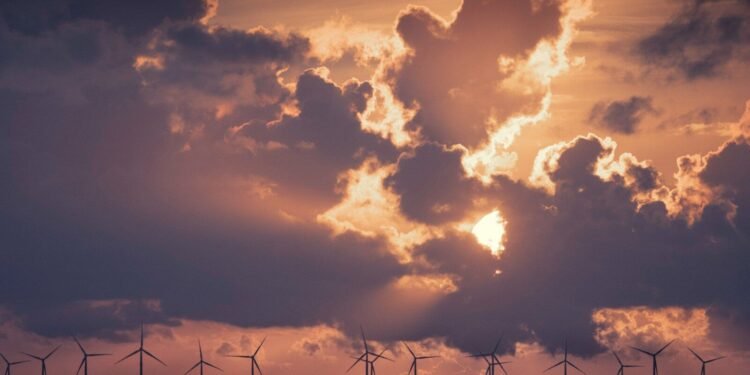 Wind turbines in the ocean under a cloudy sky with low golden light