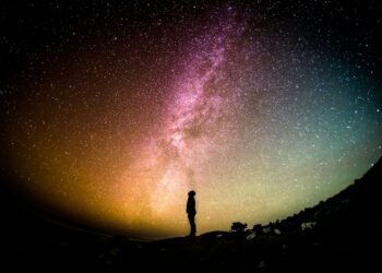 A lone silhouette standing under the Milky Way, dwarfed by the vastness of space