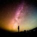A lone silhouette standing under the Milky Way, dwarfed by the vastness of space