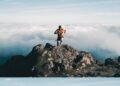 Trail runner reaching a mountain summit above the clouds, a comeback story