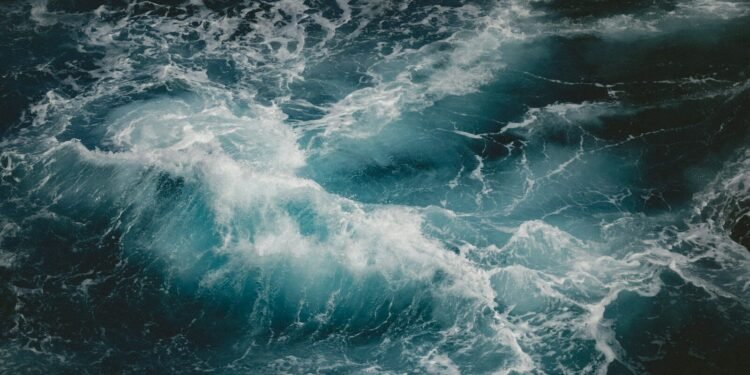 Teal wave crashing in a dark sea