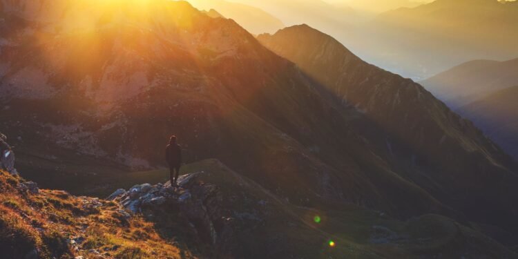 A lone hiker on a rocky mountain ridge at sunrise