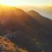 A lone hiker on a rocky mountain ridge at sunrise