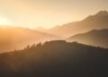 Sunrise casting warm light over a misty mountain landscape