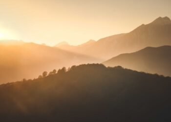 Sunrise casting warm light over a misty mountain landscape