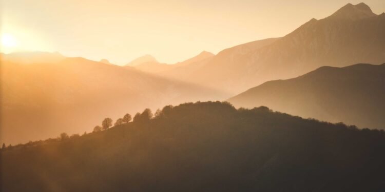 Sunrise casting warm light over a misty mountain landscape