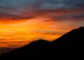 Vivid sunset behind a dark mountain silhouette