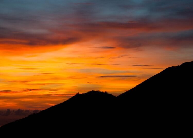 Vivid sunset behind a dark mountain silhouette