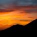 Vivid sunset behind a dark mountain silhouette