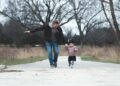 A father and young daughter walking in a park