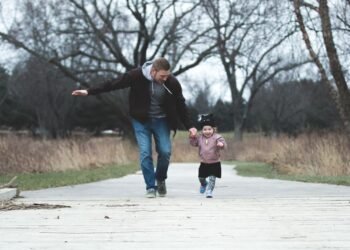 A father and young daughter walking in a park