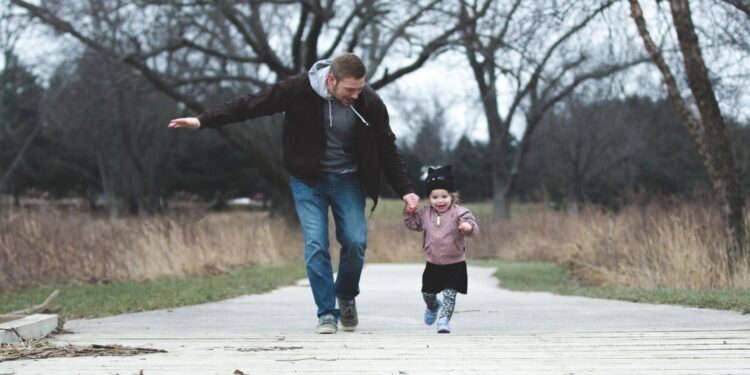 A father and young daughter walking in a park