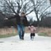 A father and young daughter walking in a park