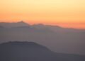 Mountain silhouettes against an orange sunrise sky