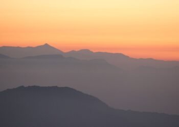 Mountain silhouettes against an orange sunrise sky