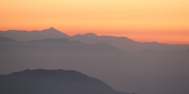 Mountain silhouettes against an orange sunrise sky