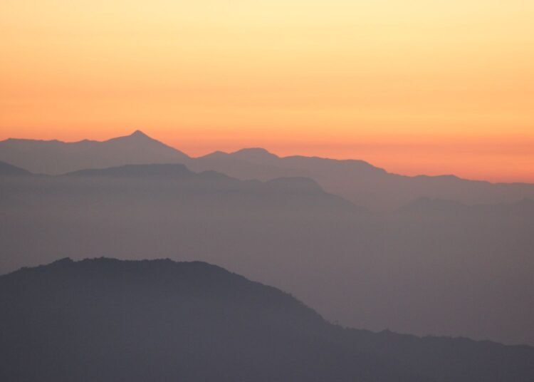 Mountain silhouettes against an orange sunrise sky