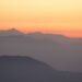 Mountain silhouettes against an orange sunrise sky