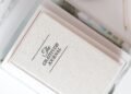 Gratitude journal on a white desk next to a cup of coffee