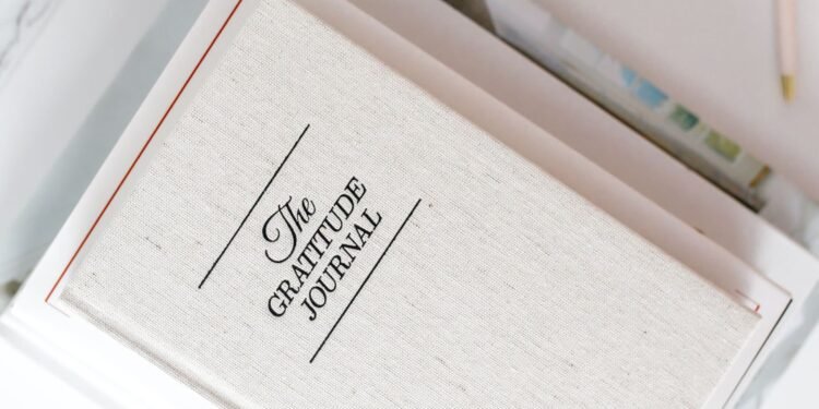 Gratitude journal on a white desk next to a cup of coffee