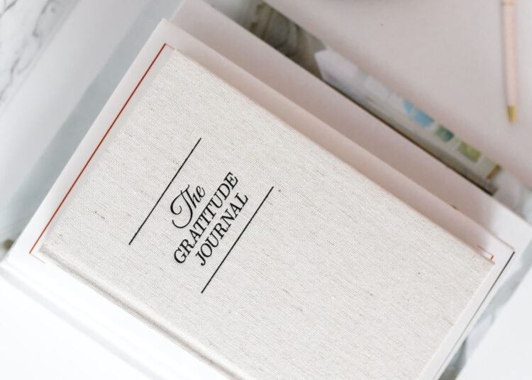 Gratitude journal on a white desk next to a cup of coffee