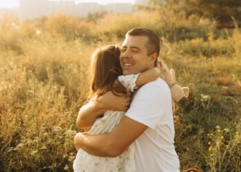 A father and daughter hugging in a sunny field, Positive Phil