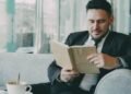 A man in a suit reading a book in a cafe, Positive Phil
