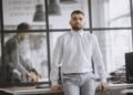 A confident man in a white shirt leaning on a desk, Positive Phil