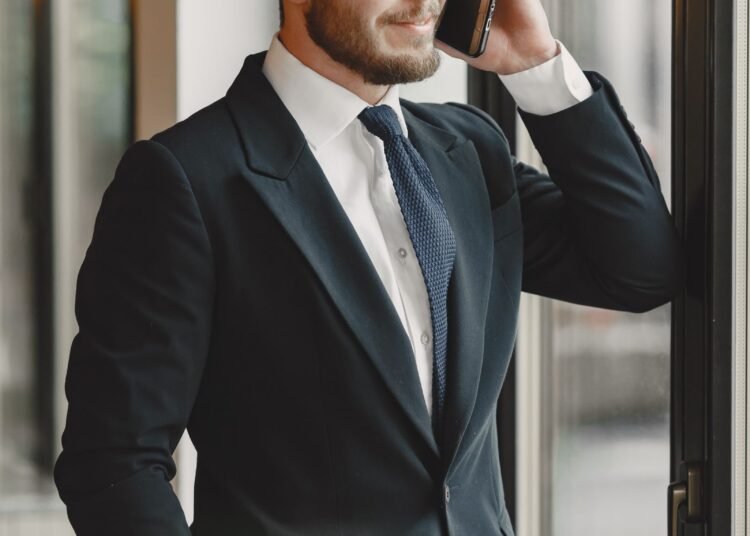 A businessman in a suit on the phone by a window, Positive Phil