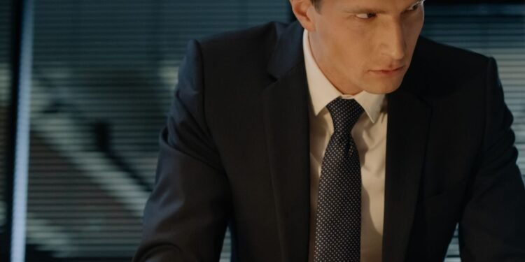 A professional man in a suit leaning over a desk, Positive Phil